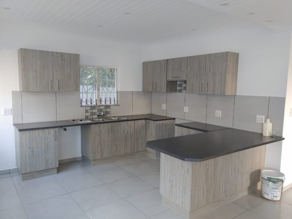 Modern grey wood-grain melamine kitchen with dark countertops in Nelspruit